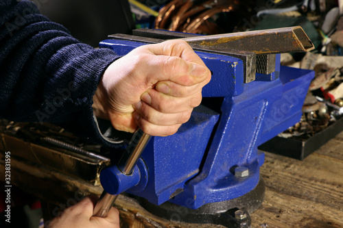 Blue vise on a wooden table. Bench tools. Vice. Men's hands hold a vise.