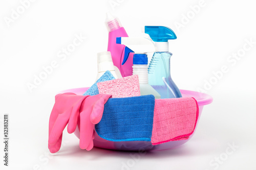 Detergent and rags in a pink basin on white background, spring cleaning concept