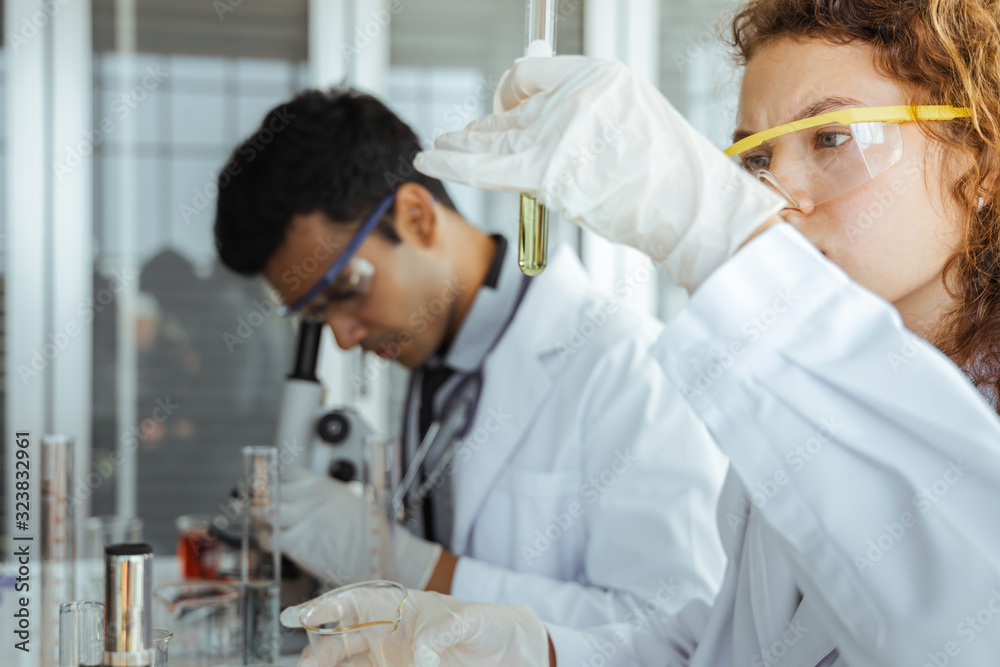 Young scientist researcher examining chemical liquid in test tube in modern laboratory. Science and medicine concept Young scientist researcher examining chemical liquid in test tube in modern laboratory. Science and medicine concept