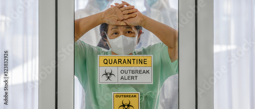 covid-19 infected patient in quarantine room with outbreak alert sign at hospital with blurred coronavirus disease control experts inside