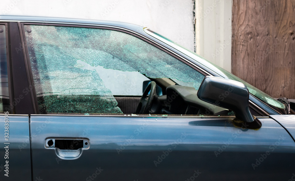 Shattered car window. Car break in. Passenger window is smashed in pieces from a thief or vandalized. Large hole.