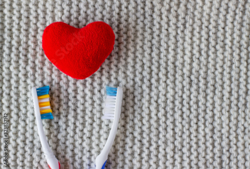 Two lovers live together. Two toothbrushes and a red heart on a knitted gray background. Love  family concept and valentines day  together forever  copy space  declaration of love