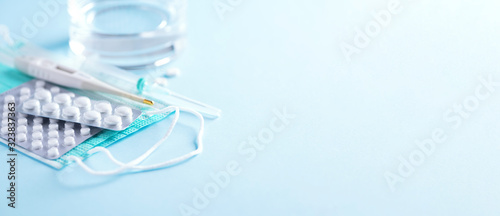 Bunch of drugs, cold flu treatment. Viral attack. Set for flu treatment - pills, capsules, thermometer, protective surgical mask, syringe. Copy space. Banner. Coronavirus Covid-19 © jchizhe