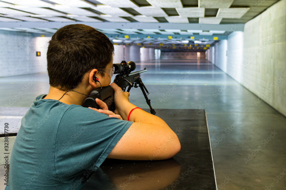 Teen learning marksmanship of shooting gun and rifle safely at firearms