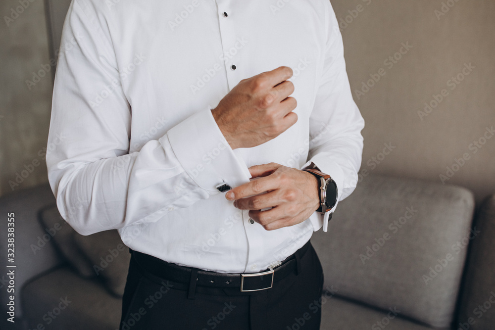 a man in a white shirt and black bowtie with a clock on his hand