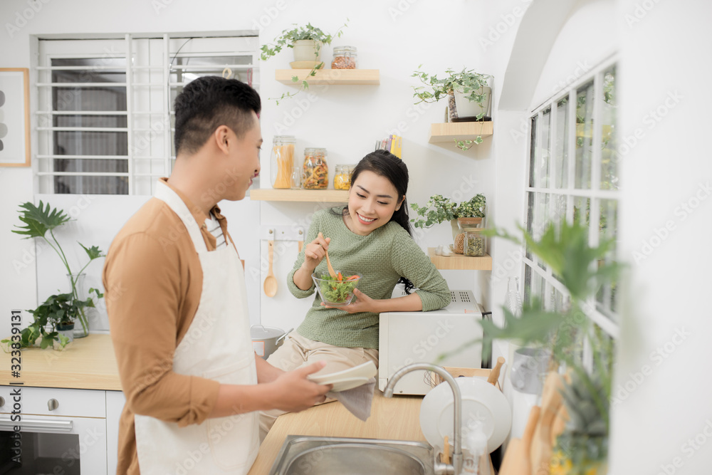 Asian couple eating breakfast early in the morning in the kitchen and having a good time.