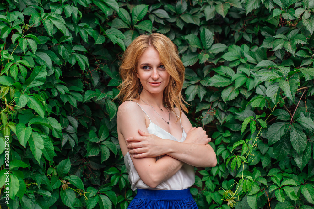 Portrait of a young beautiful woman, standing next to the wall of wild grape leaves. Portrait of a young beautiful woman, standing next to the wall of wild grape leaves.