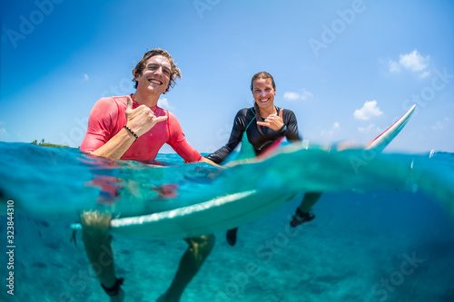 Young happy surfers man and woman sit on the surfboards in the water photo