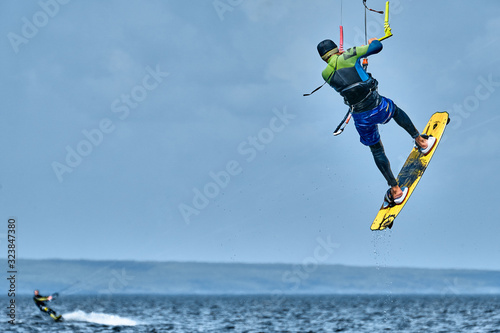 A male kiter slides on the surface of the water. Splashes of water fly apart.