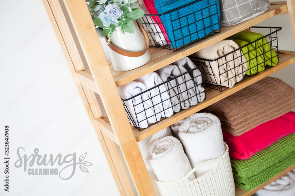Bed sheets, duvet covers and towels are folded vertically. Metal and fabric black baskets. Bedclothes bright colors.