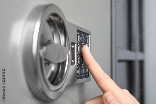 Woman opening steel safe with electronic lock, closeup photo