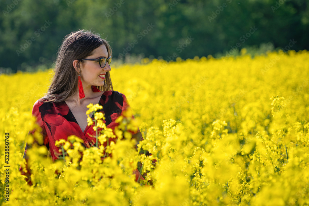 Young woman with glasses standing in yellow oilseed rape field image Young woman with glasses standing in yellow oilseed rape field image