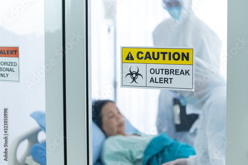 Coronavirus covid 19 disease control experts with syringe filled with coronavirus covid 19 blood sample in quarantine room with infected coronavirus patient and blurred danger quarantine room sign 