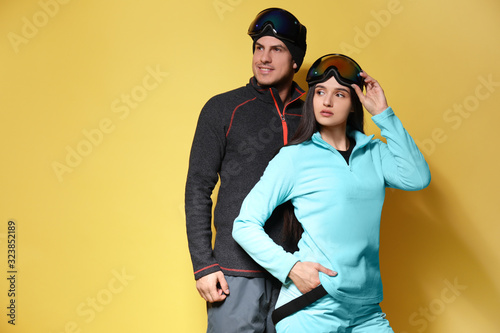 Murais de parede Couple wearing stylish winter sport clothes on yellow background