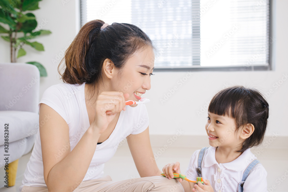 Mother teaching kid daughter teeth brushing at home Mother teaching kid daughter teeth brushing at home