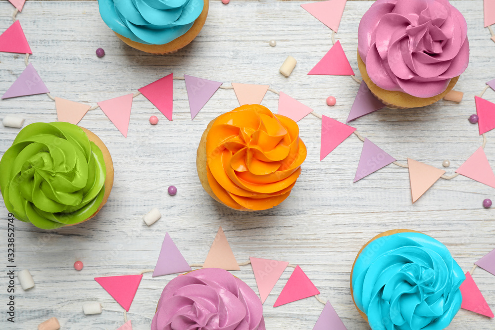 Colorful birthday cupcakes on white wooden table, flat lay Colorful birthday cupcakes on white wooden table, flat lay