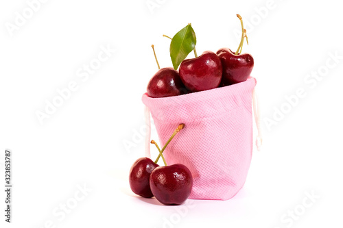 Texture of cherry in pink cloth bag isolated on white background. Sweet fresh cherry.