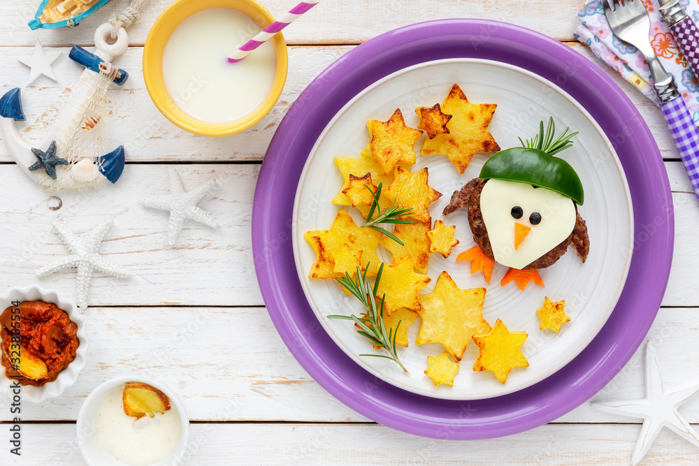 Fun Food for Kids - cute little penguin shaped beef hamburget in a hat with star shaped roast potatoes with aromatic fresh rosemary