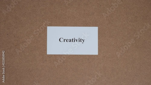 CREATIVITY. Top shot - Hand puts paper card with word. CORE VALUE concept.