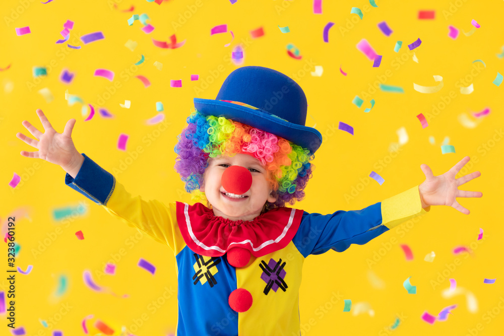 Fototapeta premium Funny kid clown playing against yellow background