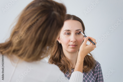 Beauty and cosmetics concept - Makeup artist doing professional make up of young woman