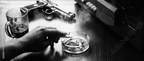 Special agent listens on the reel tape recorder. Officer is smoking a cigarette. KGB spying on conversations. Hand with cigarette near the ashtray. Gun on the table. photo