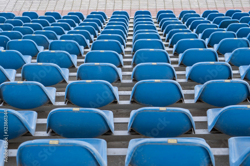 Seats in the stadium are in the background. auditorium-stands. Rows of chairs in an open-air stadium. Spectator seats.