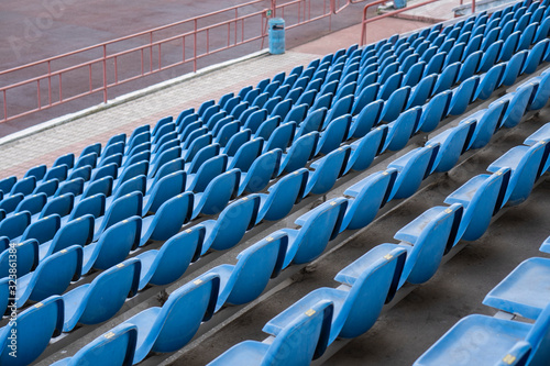 Seats in the stadium are in the background. auditorium-stands. Rows of chairs in an open-air stadium. Spectator seats.