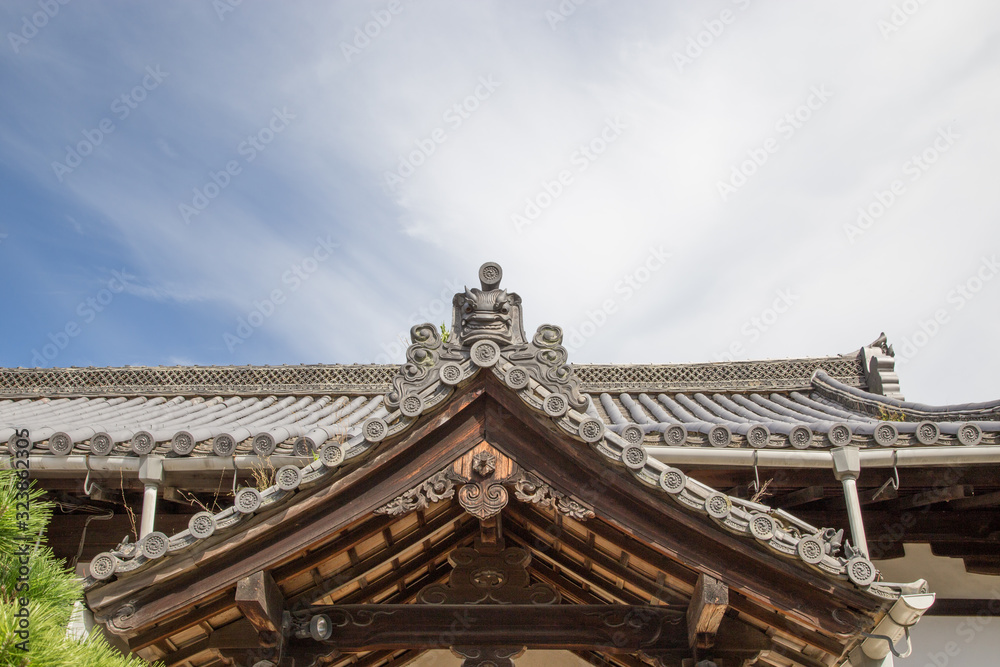 Detail of the decoration of an old Japanese wooden house with the sky in the back Detail of the decoration of an old Japanese wooden house with the sky in the back