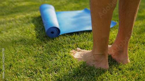 Man is going yoga practice outdoors on a sunny meadow. Yoga legs concept