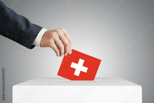 Принти на полотні Man putting a voting ballot into a box with Switzerland flag.