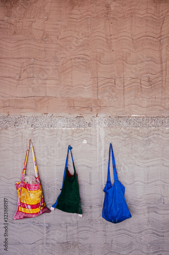 Multicolour Tote bags hanging on  old concrete wall photo
