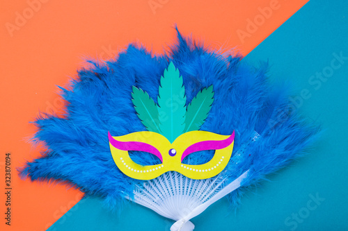Flat lay of mask on feathers fan for carnival