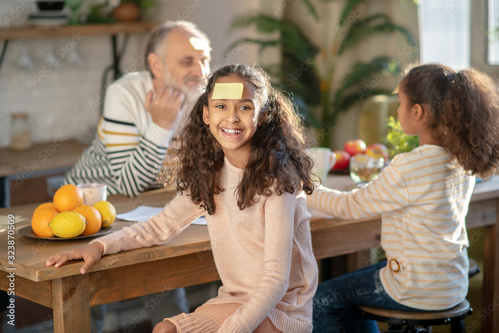 Fototapeta premium Two dark-skinned girls playing guess game with their granddad