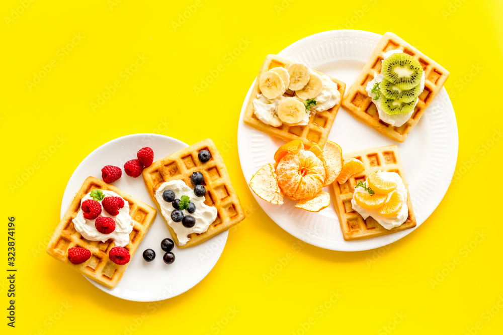 Belgian waffles with creamy cheese and berries on yellow background top-down Belgian waffles with creamy cheese and berries on yellow background top-down