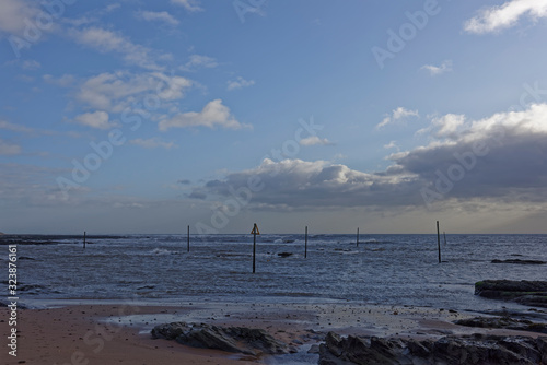 The upright wooden Rock Markers of Westhaven Beach at Low tide and in windy conditions after Storm Dennis. photo