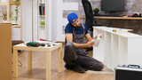 Male worker talking on the phone while assembles white furniture