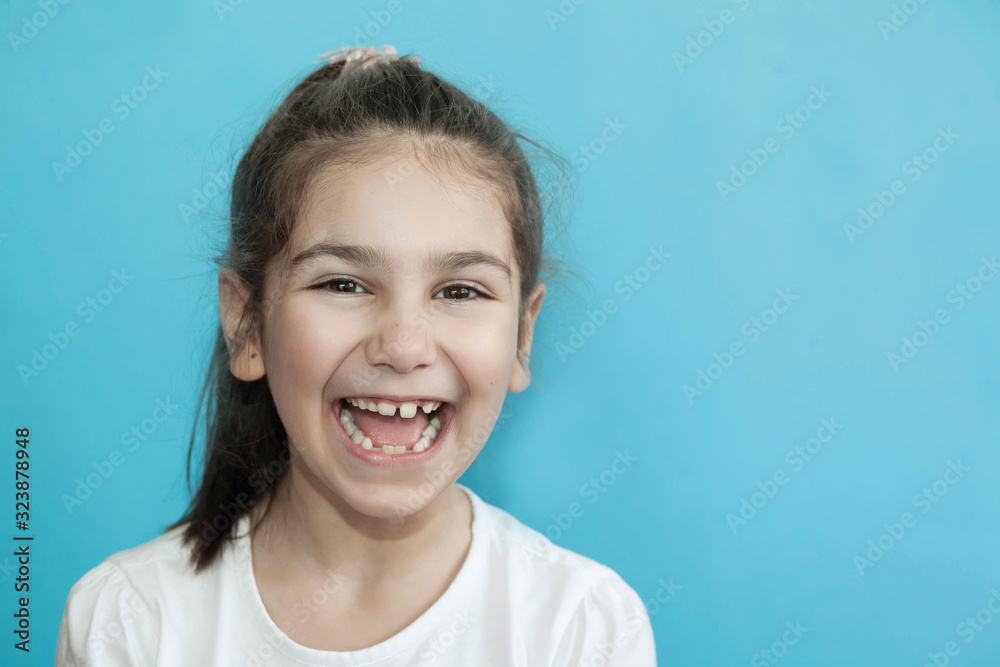 Portrait of happy laughing child girl on blue background. Smiling kid. Positive emotions. Portrait of happy laughing child girl on blue background. Smiling kid. Positive emotions.