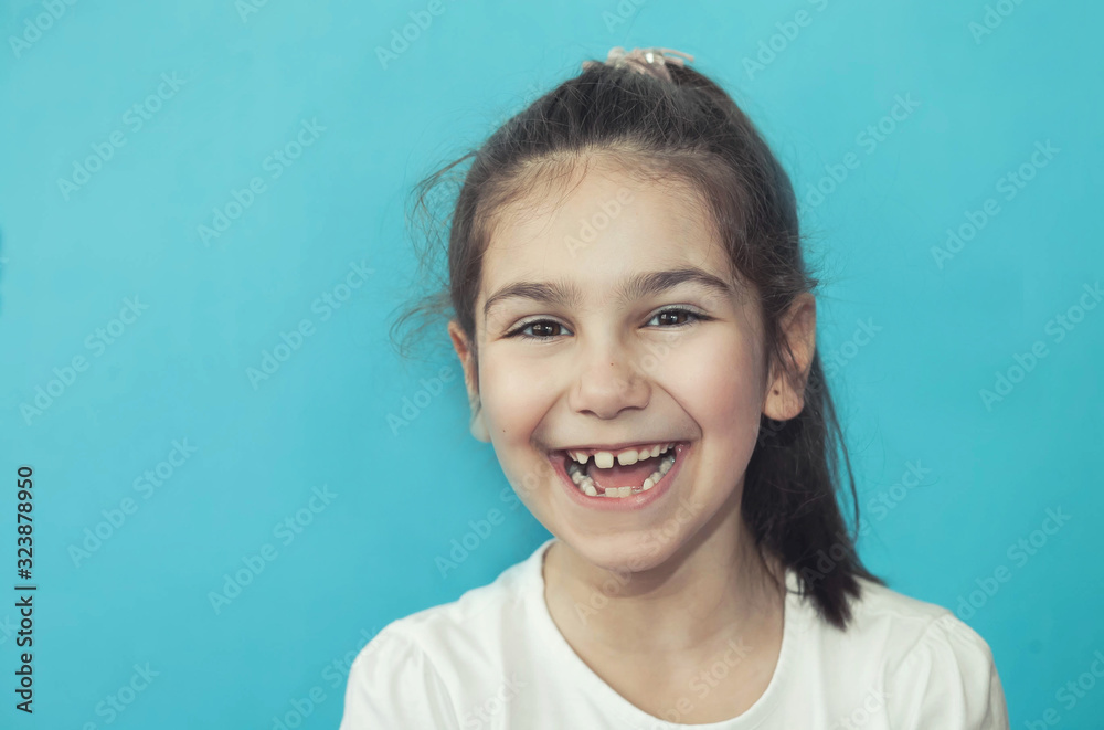 Portrait of happy laughing child girl on blue background. Smiling kid. Positive emotions. Portrait of happy laughing child girl on blue background. Smiling kid. Positive emotions.