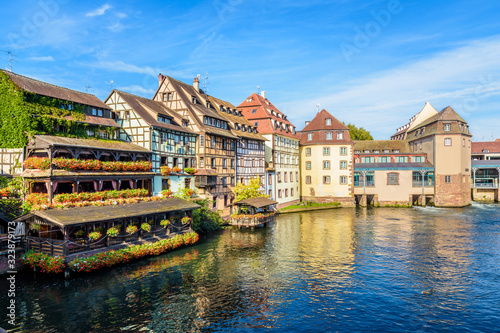 Typical half-timbered buildings and former water mills with pastel facades lining the river Ill in the Petite France quarter in Strasbourg, France, on a sunny morning.