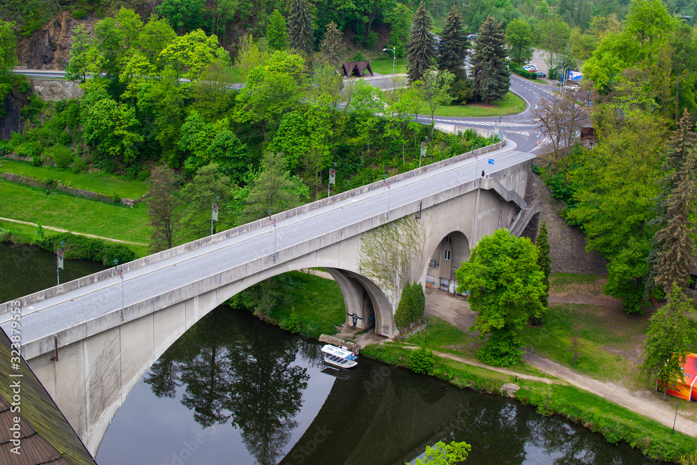 Loket, Czech Republic; 5/20/2019: Arch bridge in Loket, reflected in the water of Ohre river, with trees at the background