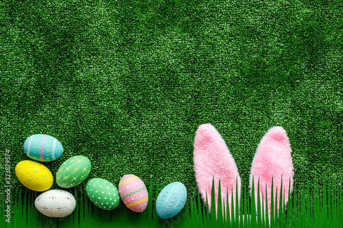 Easter concept. Eggs, Bunny's ears on green grass background top-down copy space