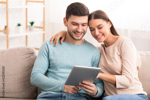 Couple Using Digital Tablet Hugging Watching Film At Home