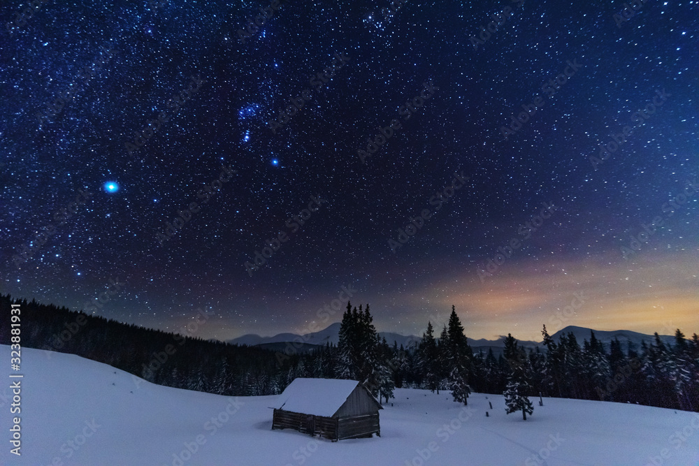 A bright starry night in the mountains with the Milky Way in the sky, Venus and millions of stars highlighting beautiful mountain huts in the valley.