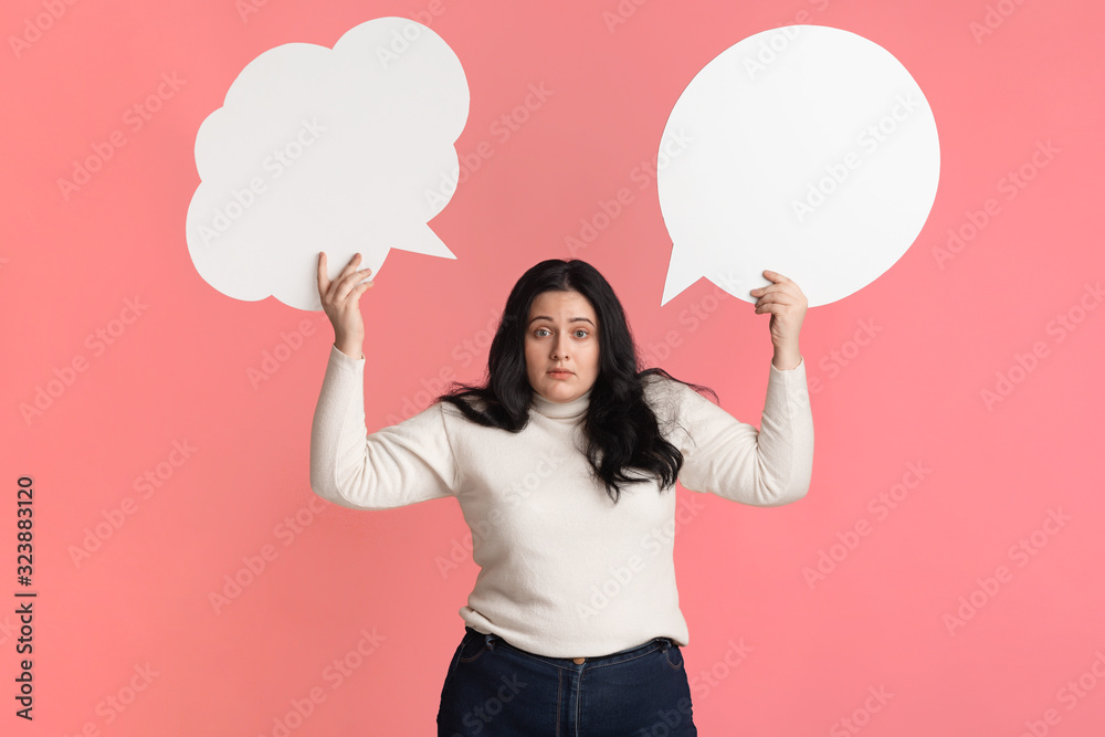 Difficult choice. Concerned plump woman holding two empty speech bubbles Difficult choice. Concerned plump woman holding two empty speech bubbles