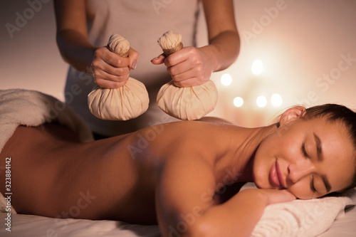 Full relaxation. Woman enjoying massage with hot herbal balls