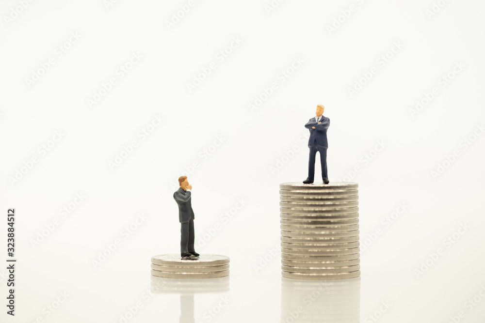 Business man miniature people figure looking and thinking for man success on top of stack of silver coin with copy space using as saving, business, and financial concept. Business man miniature people figure looking and thinking for man success on top of stack of silver coin with copy space using as saving, business, and financial concept.