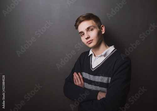 Lifestyle photo of a young brown-haired man on a light background, a beautiful young guy in a shirt and sweater