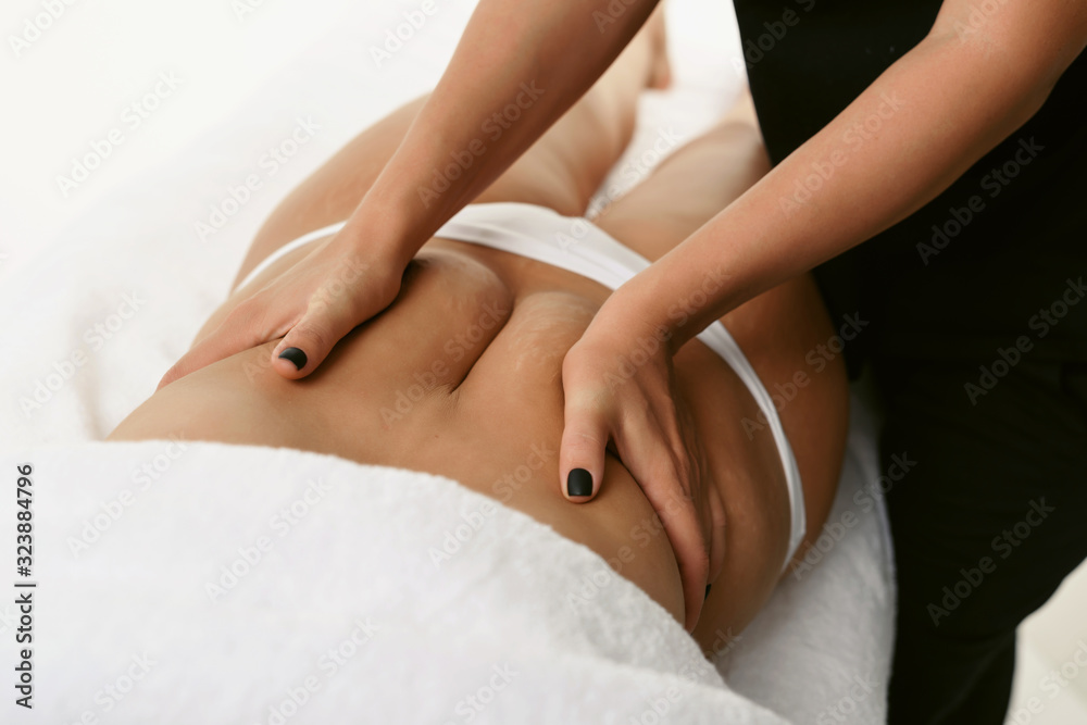 Fat burning massage belly after pregnancy. Masseur making anti cellulite therapy for young woman in wellness center or beauty salon. Perfect skin beauty concept Fat burning massage belly after pregnancy. Masseur making anti cellulite therapy for young woman in wellness center or beauty salon. Perfect skin beauty concept