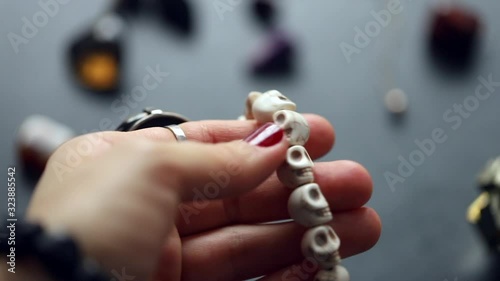 Witch's hands sort out beads from white bone skulls.  photo